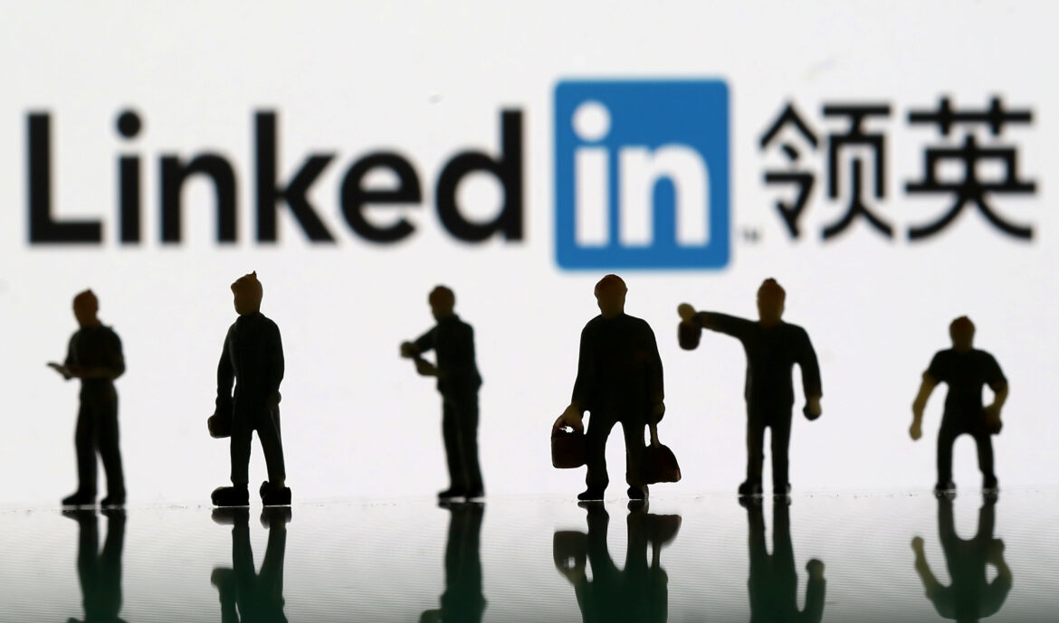 Small toy figures are seen between displayed U.S. flag and Linkedin logo in this illustration picture