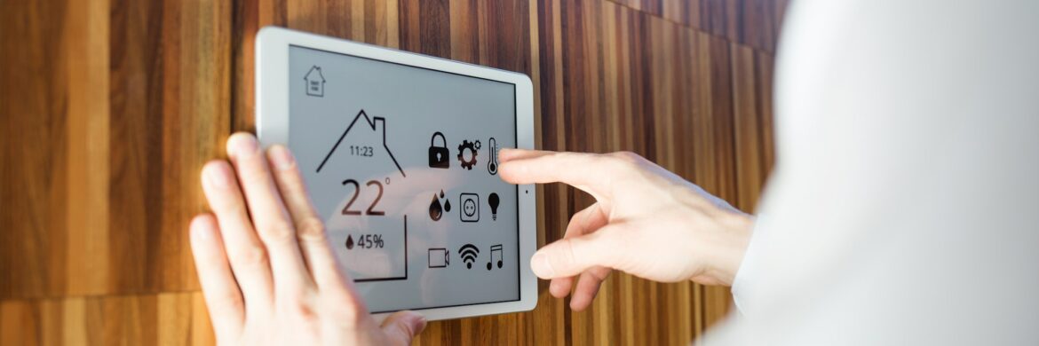 man controls smart home devices using digital tablet with launched application on background of wall تعرف على أهم النقاط قبل اختيار أجهزتك المنزلية الذكية