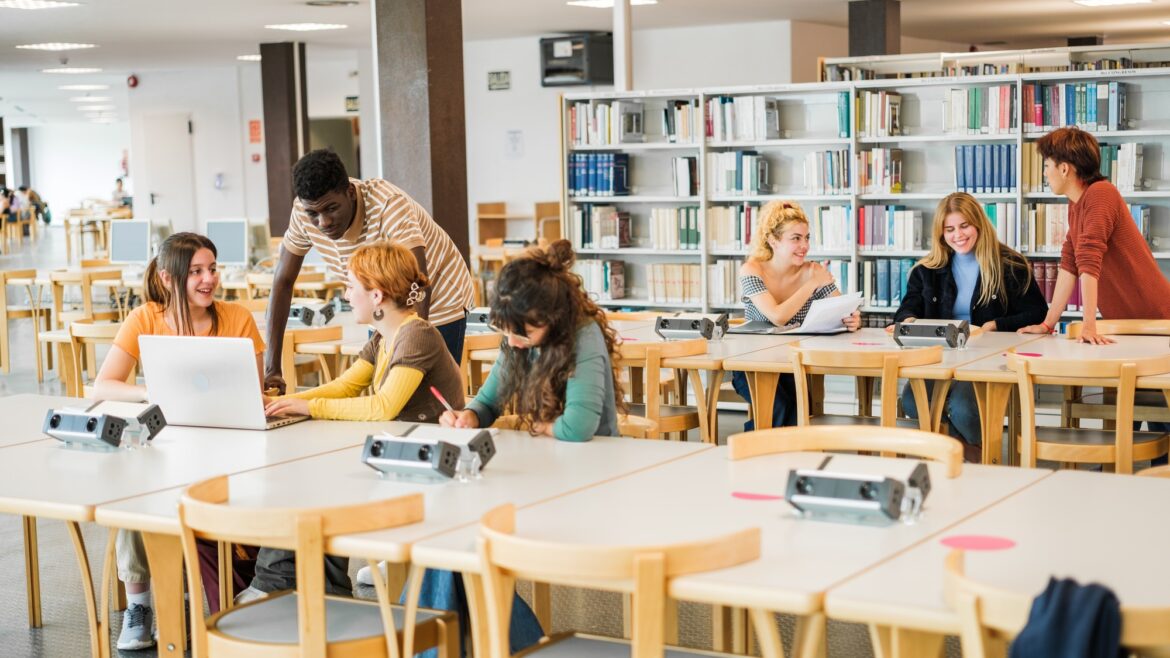 Group of students studying in the university library together and sharing moments