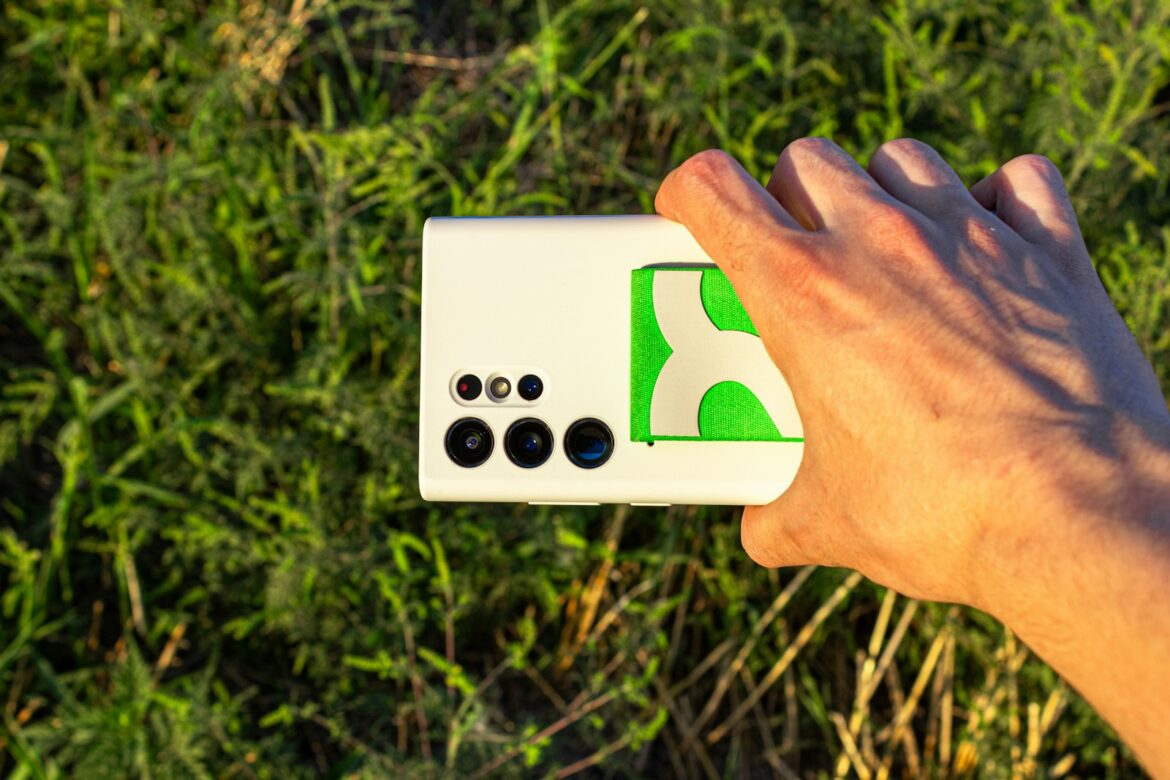A hand is holding a white and green device