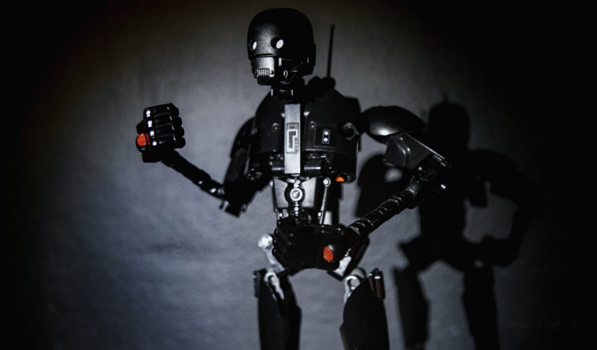 A spooky black robot toy dropping a shadow on a black wall.