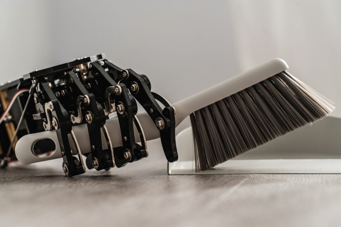 Robotic hand skillfully using a dustpan and brush to sweep the floor