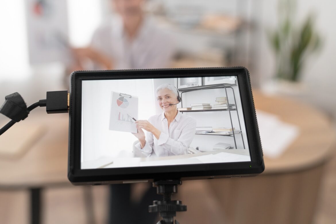 Caucasian mature businesswoman broadcasting while explaining graphs online on live translation.