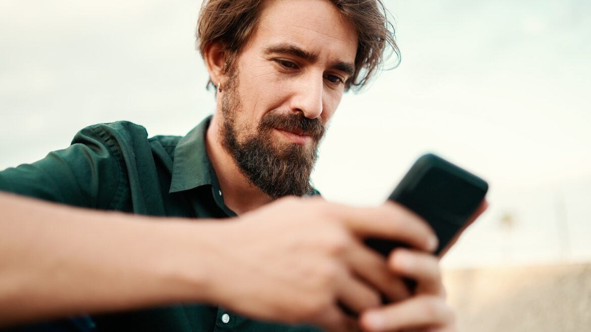 Closeup of a young hipster male using a mobile phone