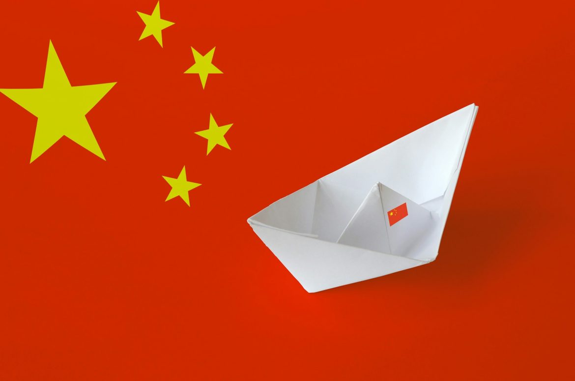 China flag depicted on paper origami ship closeup. Oriental handmade arts concept
