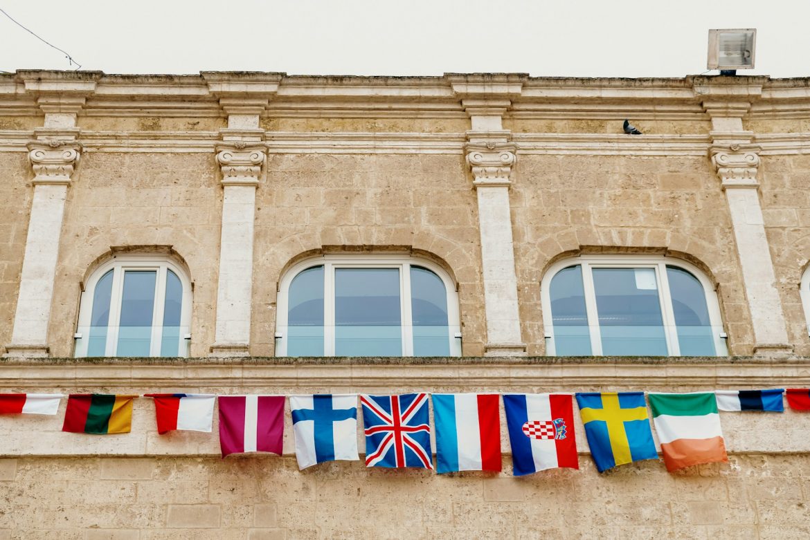 Flags of European countries hanging from a balcony in the Italian city of Matera.