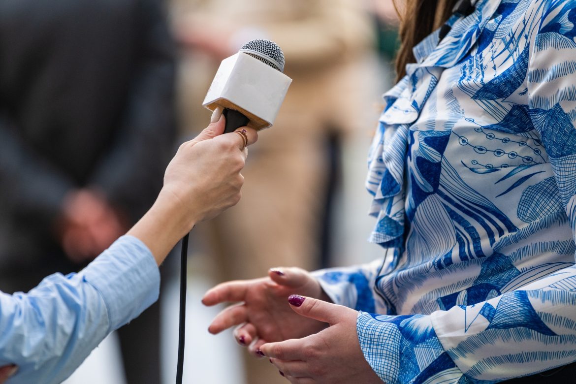 A journalist conducts an interview, capturing reactions and insights during the opening ceremony