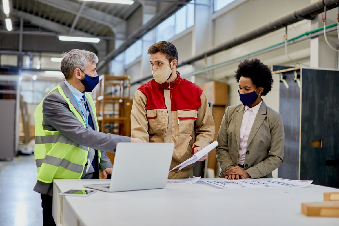 Woodworking company managers communicating with male worker at production facility.