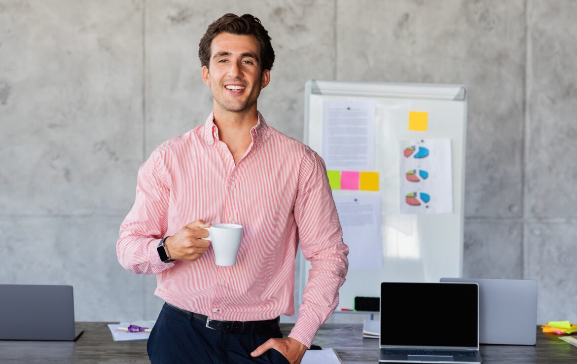 Happy young businessman drinking coffee after successful business meeting