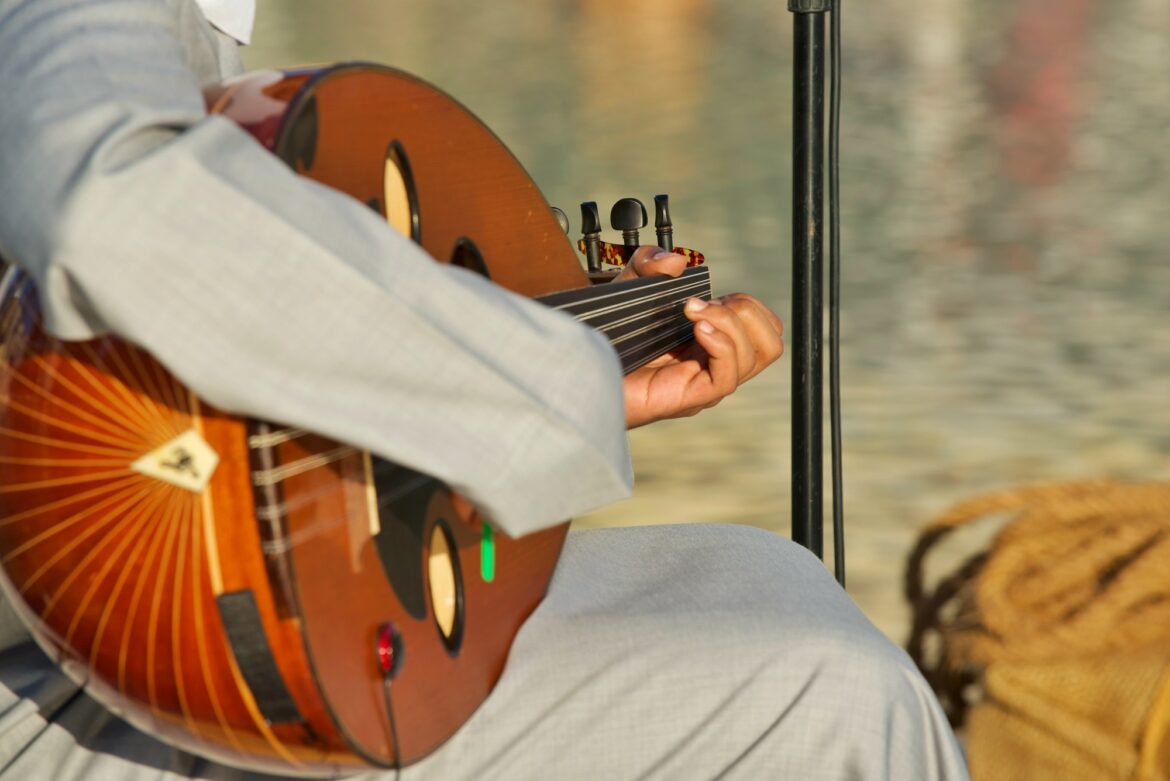 Middle East unrecognizable musician wearing traditional clothing plays a multi string oud instrument