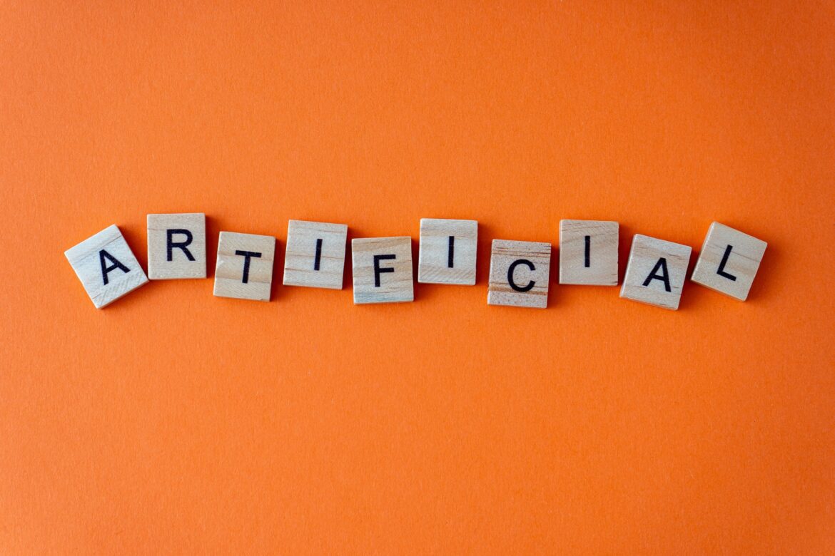 Word artificial. The phrase is laid out in wooden letters top view. Orange flat lay background.