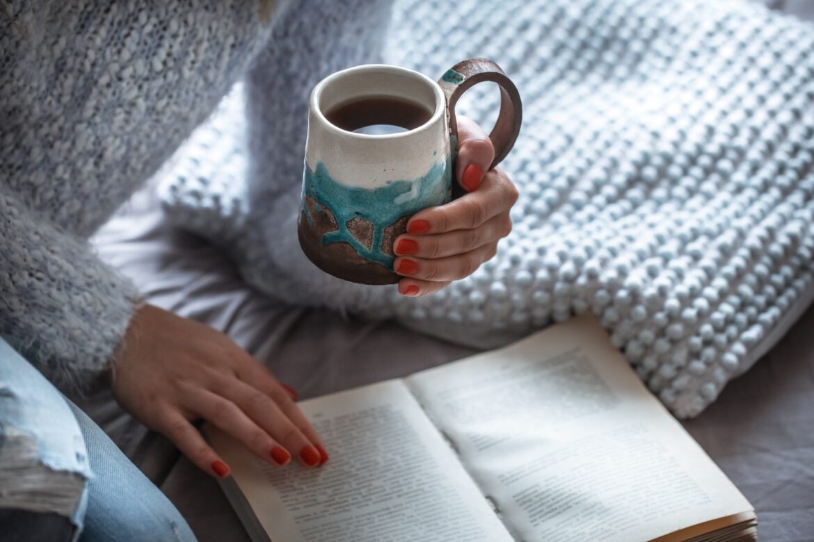 girl holds a cup and reads book