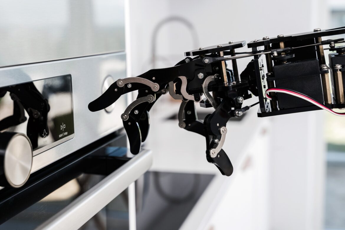 Real robot's hand and electric oven. Concept of robotic process automation