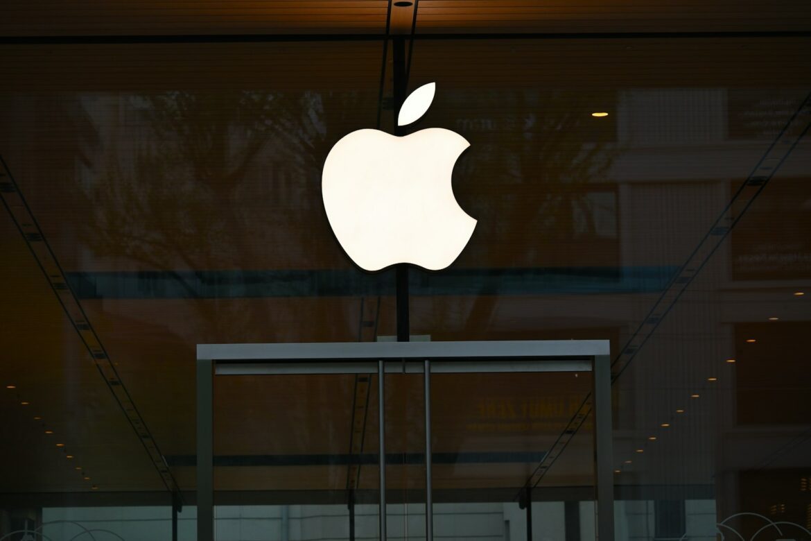 the apple logo is reflected in the glass of a building